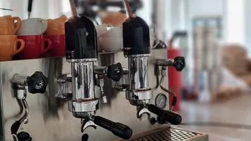 Espresso machine with cups in cafe.