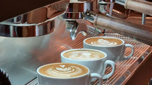 Espresso machine making coffee with latte art.