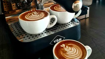 Three lattes on espresso machine drip tray.