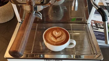 Latte art coffee on espresso machine tray.