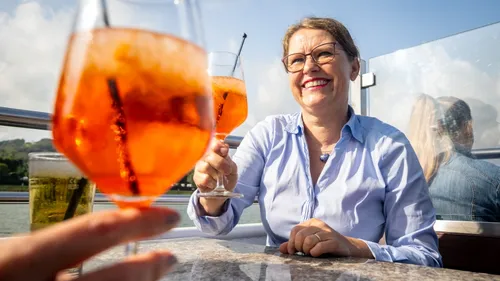 Person toasting drinks on a sunny patio.