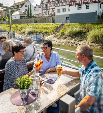 People enjoying drinks on boat, riverside view.