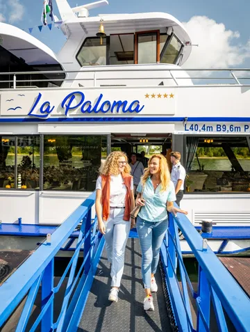 Two women walking off blue gangway from boat.