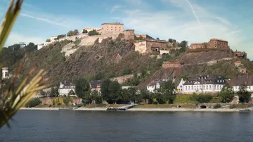 Fortress on hill overlooking riverside town.