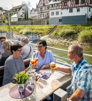 Drei Personen genießen Getränke auf einem Boot.