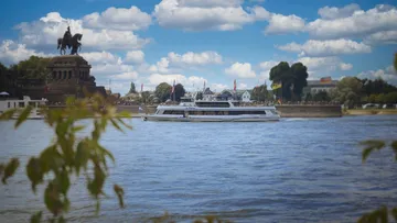 Boat sailing near monument on riverbank.