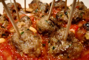 Meatballs with toothpicks in tomato sauce.