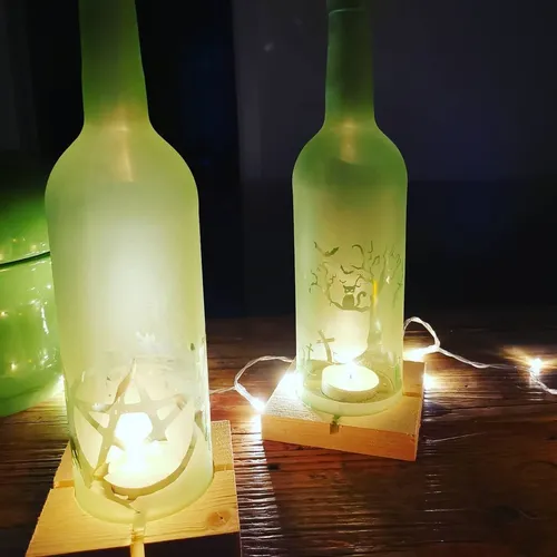 Two illuminated green bottles on wooden bases.