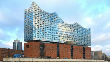 Modernes Konzerthaus mit welligem Dach, städtische Umgebung.