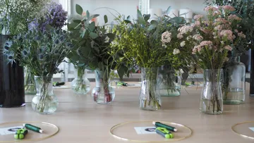 Flowers in vases are placed on a table with pens.