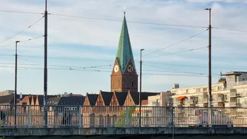 Kirche mit Uhrturm hinter Brücke, Abendlicht.