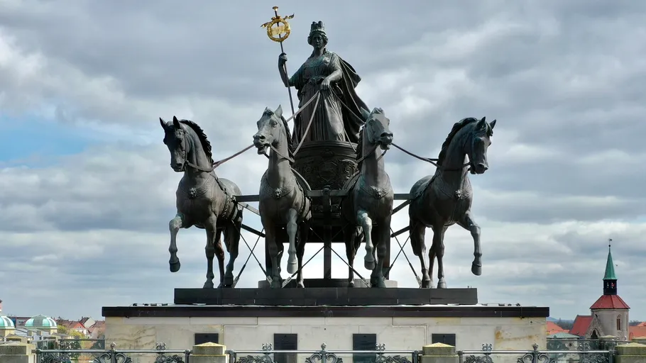 Bronzene Quadriga-Statue auf einem historischen Tor.