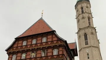 Rotes Dachgebäude neben hohem Kirchturm.