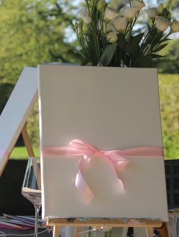 Blumenvase auf Leinwand mit rosa Schleife.