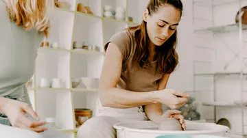 Woman shaping clay in pottery studio.