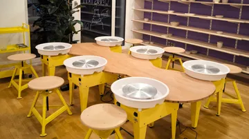 Töpferstudio mit Drehscheiben und Hockern.