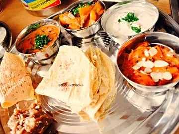 Stews and bread served on a metal plate.