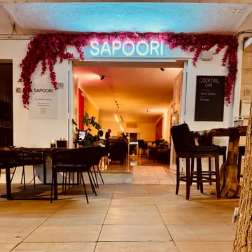 Restaurant entrance with neon sign and seating.