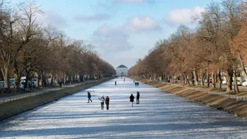 Menschen gehen auf gefrorenem Kanal, Winterbäume.