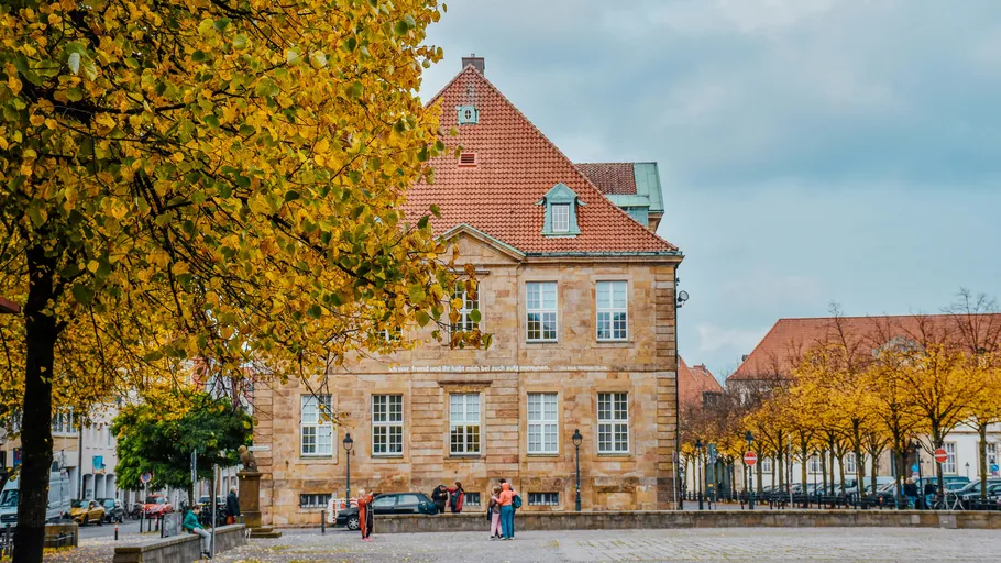 Historic building with trees, people nearby.