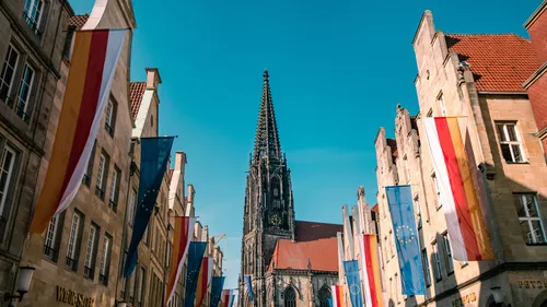 Gotische Kirche umgeben von Gebäuden und Fahnen.