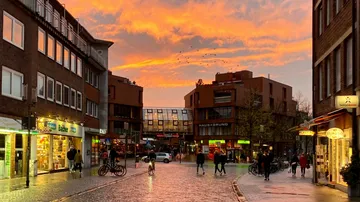 People walking in city during vibrant sunset.