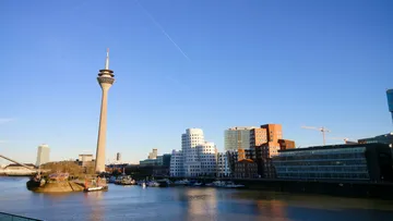 Stadtansicht mit Turm, Gebäuden und Fluss.