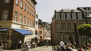 People dining outdoors on cobblestone street.