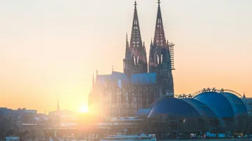 Kölner Dom mit Sonnenuntergang im Hintergrund.