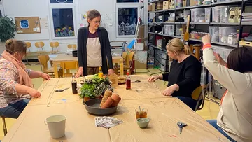 Women crafting at a table in a workshop.