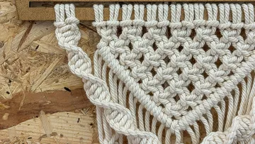 Macrame wall hanging on wooden board.