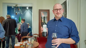 Mann hält Weinflasche und Glas drinnen.