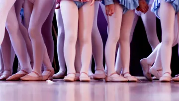 Beine von Balletttänzern in Strumpfhosen und Schuhen.