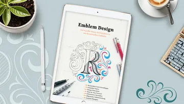 Tablet zeigt Anleitung für Emblem-Design auf Tisch.