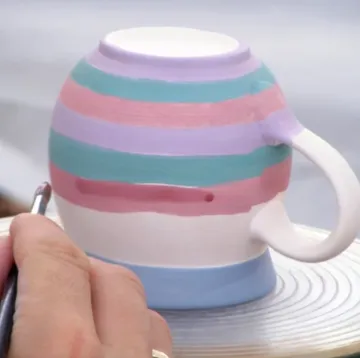 Person malt bunte Streifen auf einen Becher.