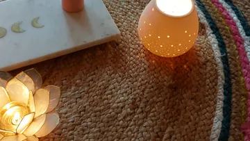 Candle holders on woven rug with mat.