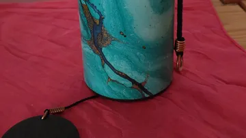 Bunter Zylinder mit Schnur auf rotem Stoff.