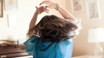 Woman dancing energetically indoors, hair flying.