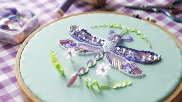 Beaded dragonfly embroidery on green fabric.