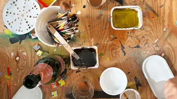 Kunstmaterialien auf Holztisch, Farbspritzer.