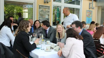 Menschen unterhalten sich im Freiluftcafé, lächeln.