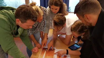 Gruppe löst Puzzle auf Tisch innen.