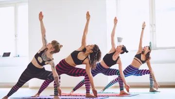Vier Frauen machen Yoga in hellem Raum.