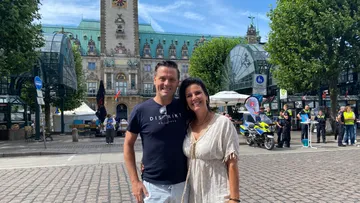 Two people standing in a city square.