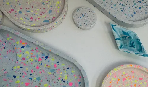 Colorful terrazzo trays and coasters on white surface.