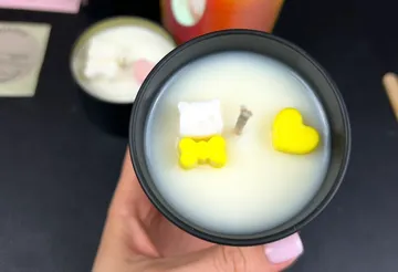 Hand holding candle with cute yellow decorations.