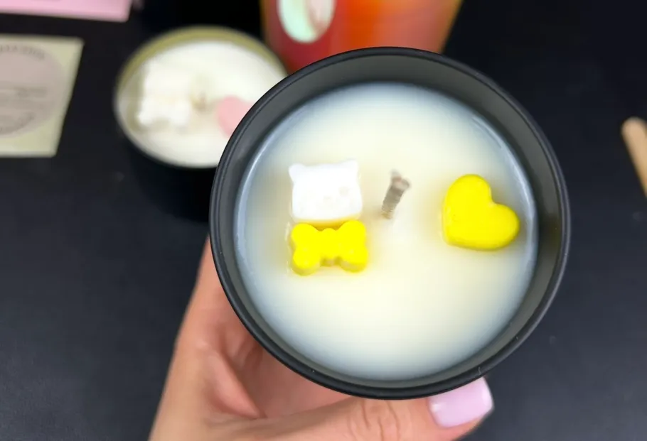 Hand hält Kerze mit niedlichen gelben Verzierungen.