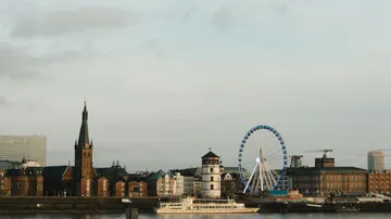 Cityscape with church, ferris wheel, and river.