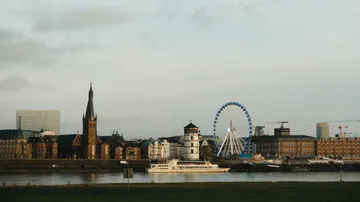 City skyline with ferris wheel by river.