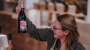 Person smiling, holding wine bottle indoors.